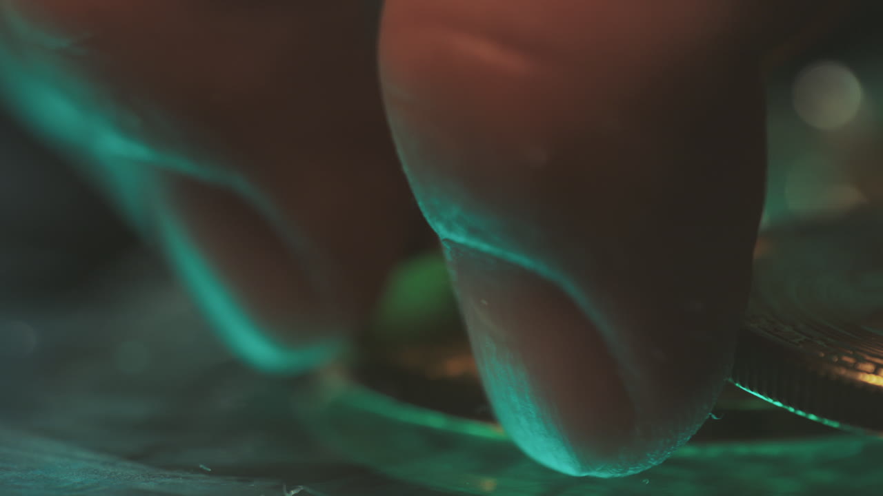 Close up of fingers handling gold coin