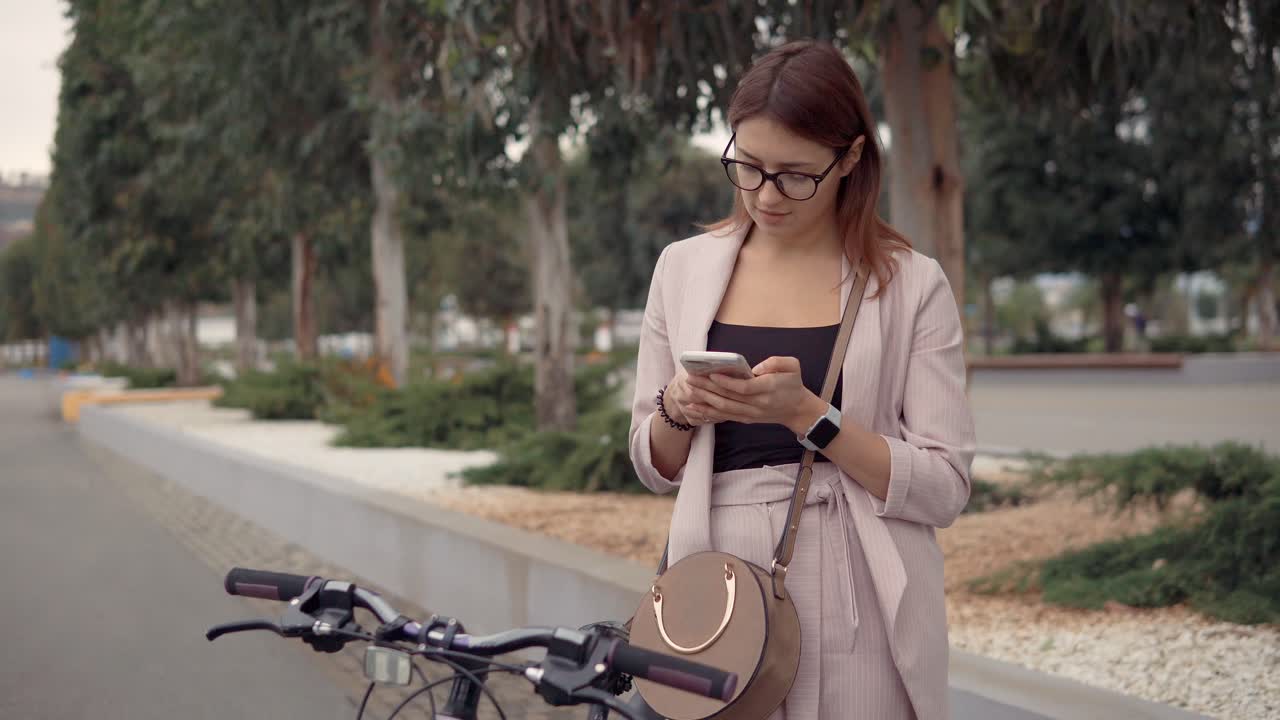 mujer usando un teléfono inteligente al aire libre cerca de una bicicleta