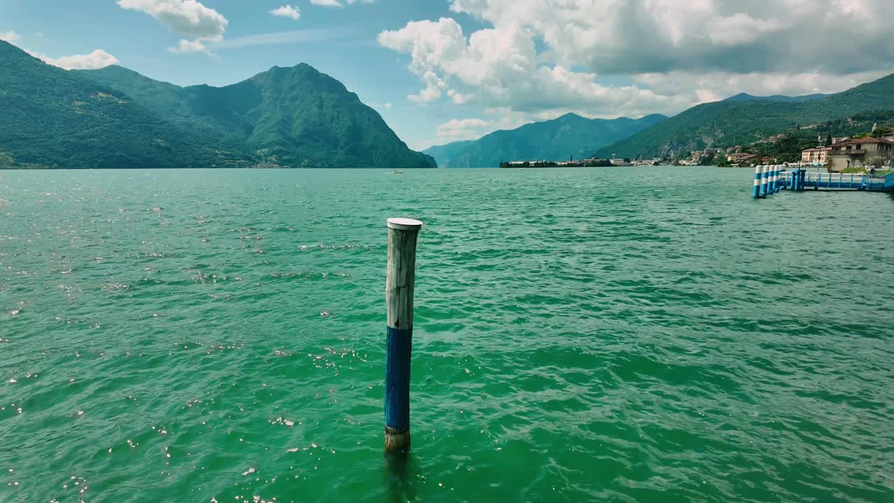 Hyperlapse singolo palo di navigazione nelle acque verde smeraldo del Lago d'Iseo con catena montuosa in lontananza, ripresa timelapse