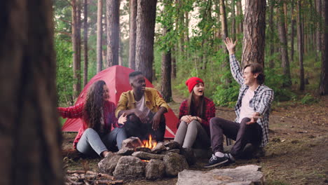 friends camping around campfire in forest