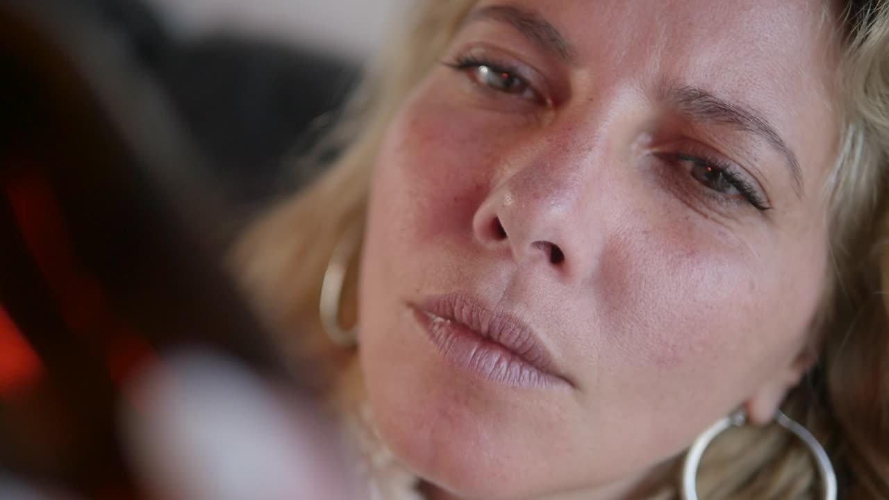 Primo piano del viso di una donna mentre legge l'etichetta su una bottiglia di medicinale