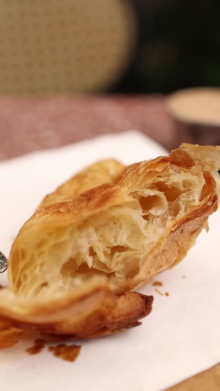 Primo piano di un croissant sfogliato che rivela i suoi strati dorati