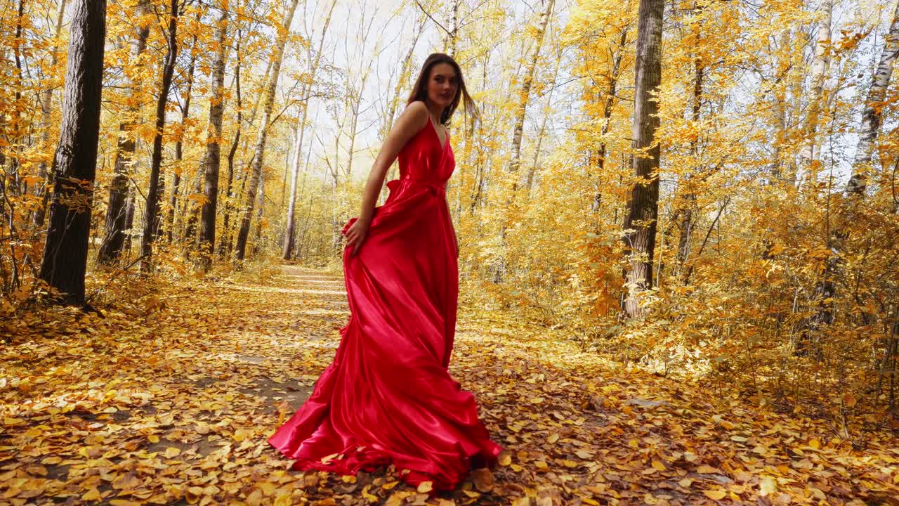 A Graceful Figure in a Flowing Red Dress Walking Through a Vibrant Autumn Forest, Surrounded by Golden Leaves and Lush Trees Under a Bright Sky