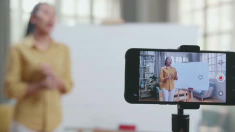 close up of smartphone camera recording asian female teacher with marker pen teaching english at home
