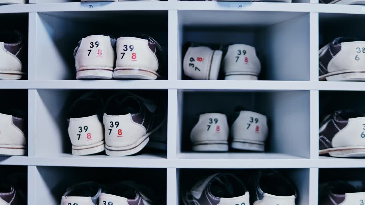 Hand reaching for numbered bowling shoes from shelf before leisure game activity
