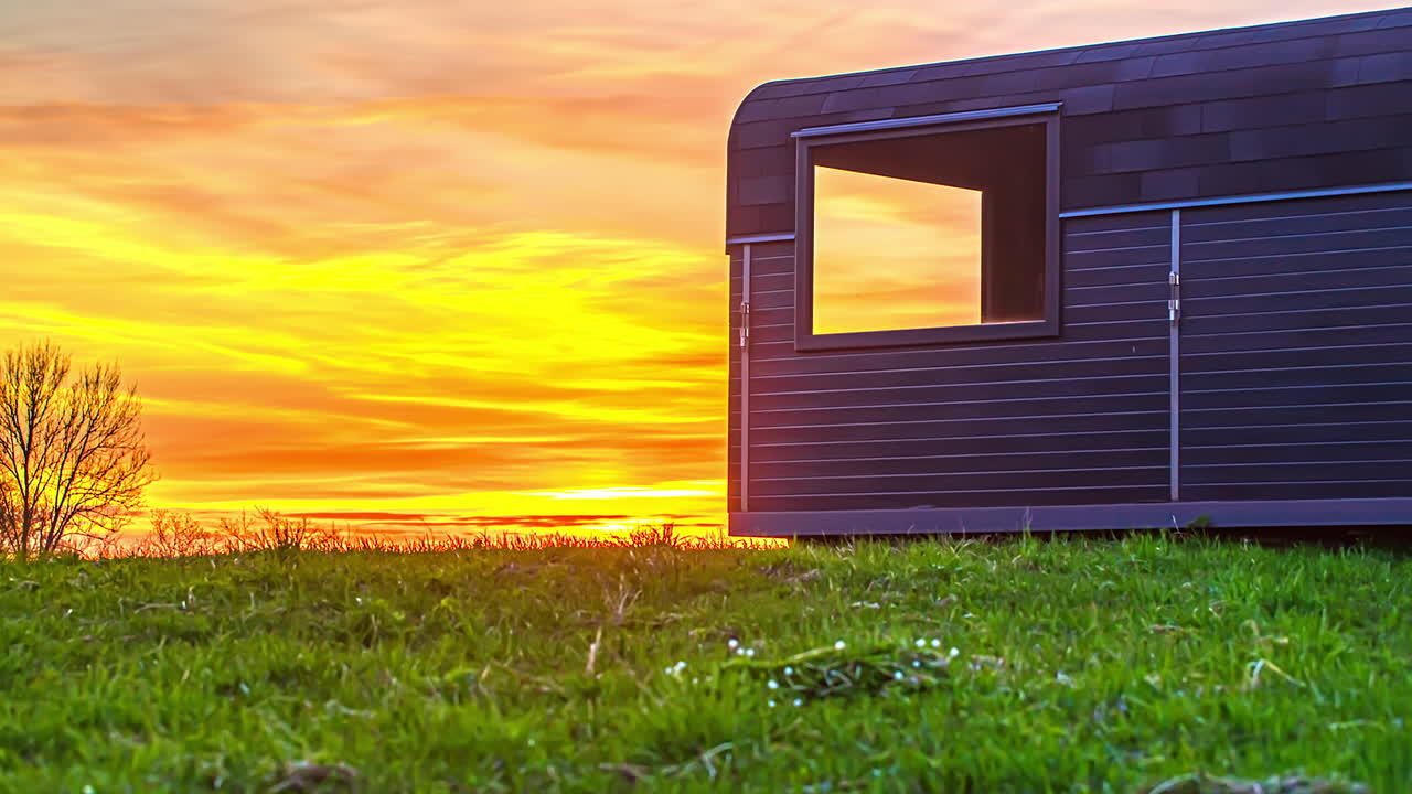 전경에 나무 오두막이 있는 시골 들판에서 황금빛 일몰과 함께 아름다운 여름날의 저속 촬영 - 하늘에서 구름을 날다