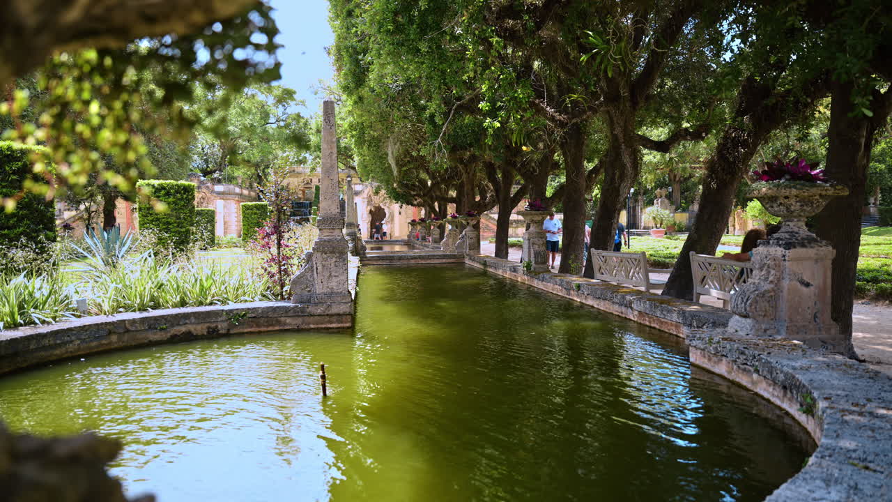 Miami, USA, 16 aprile 2026: Specchio d'acqua nel giardino tropicale di Vizcaya. Lungo specchio d'acqua circondato da alberi e sculture in pietra nei giardini di Vizcaya a Miami.