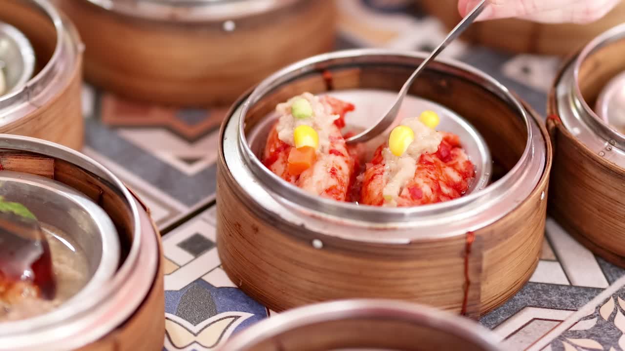 A spoon lifts dim sum from bamboo steamers, highlighting vibrant colors and textures.