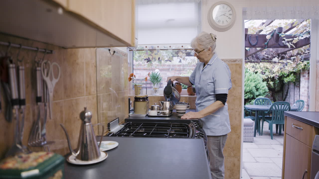 Donna anziana che versa il tè in cucina