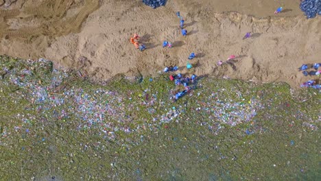 muchos ayudantes limpiando la playa sucia y el océano de la república dominicana - catástrofe ambiental con basura en el mar - aérea de arriba hacia abajo