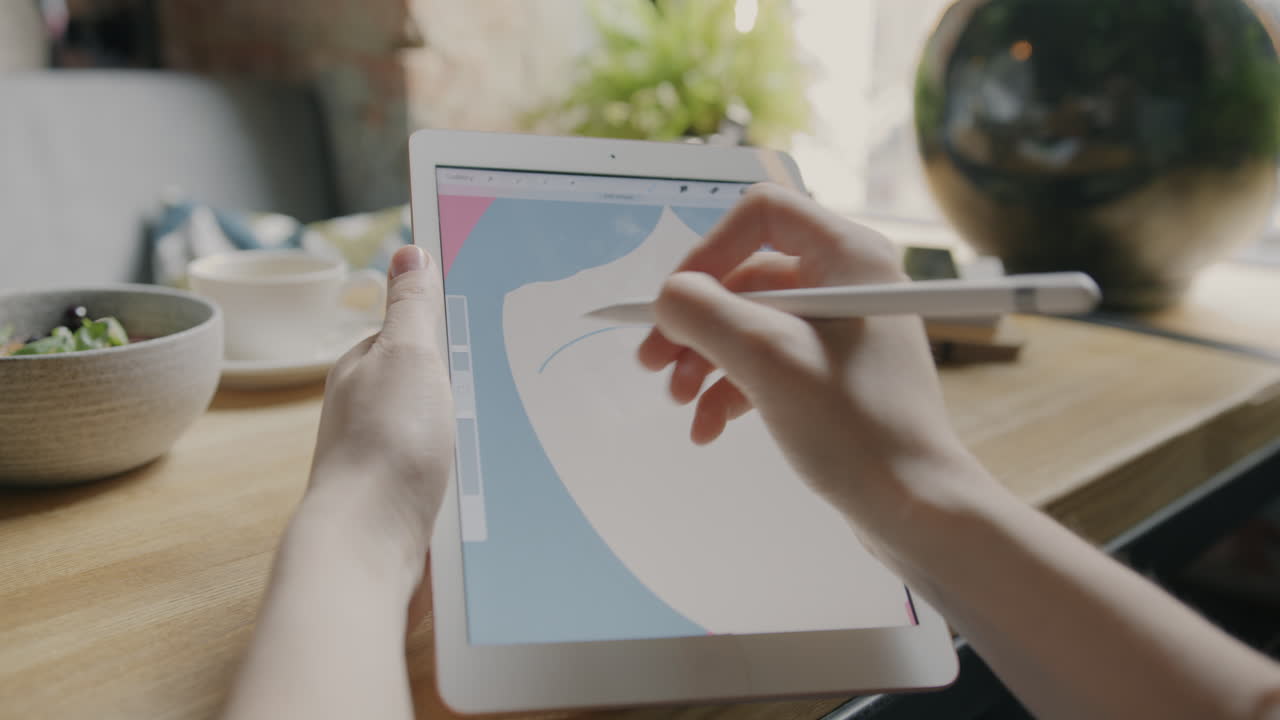 Woman Drawing on Tablet in a Cafe