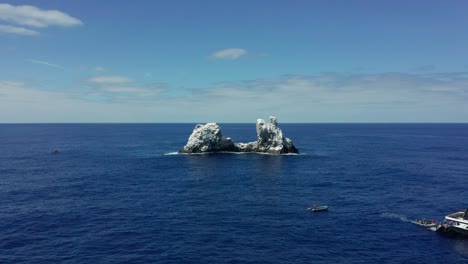 Dive-boat-near-guano-covered-Roca-Partida-rocky-islet-in-Pacific,-aerial