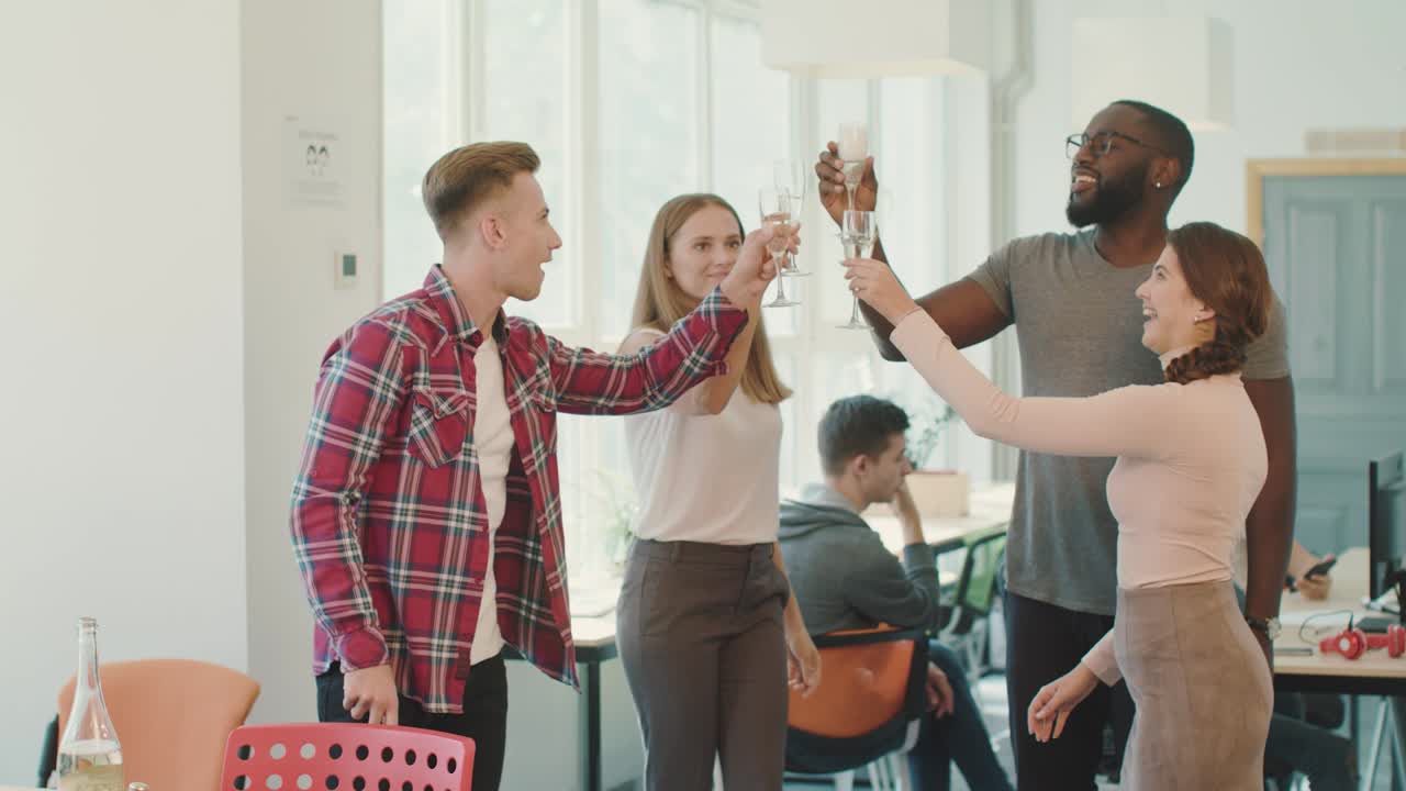 Happy people giving toast at coworking space. Smiling friends drinking together