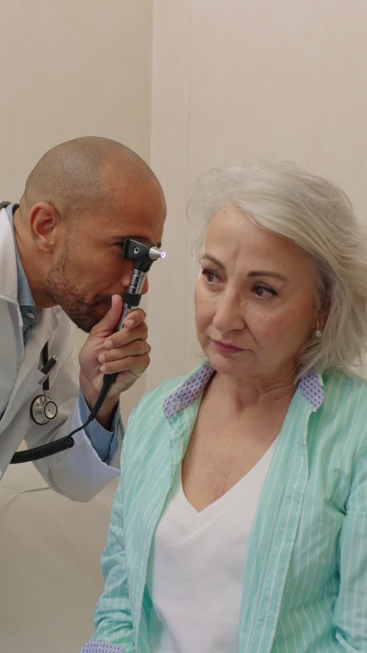 Doktor, bir otoskopla yaşlı bir kadını muayene ediyor
