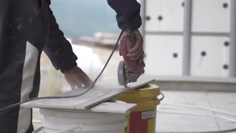 SLOWMOTION-Close-up-of-labourer-hand-cutting-tile-with-grinder