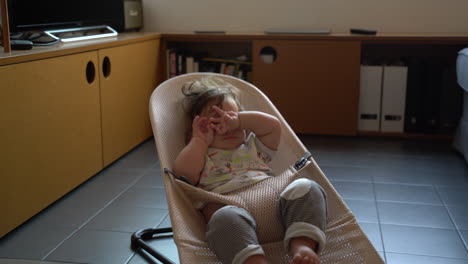 impatient tired bored baby toddler bouncing up and down chair at home, static