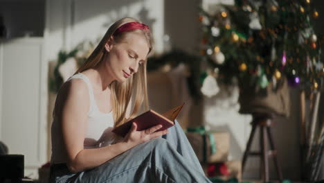 mujer atractiva leyendo un libro mientras está sentada en casa durante la navidad