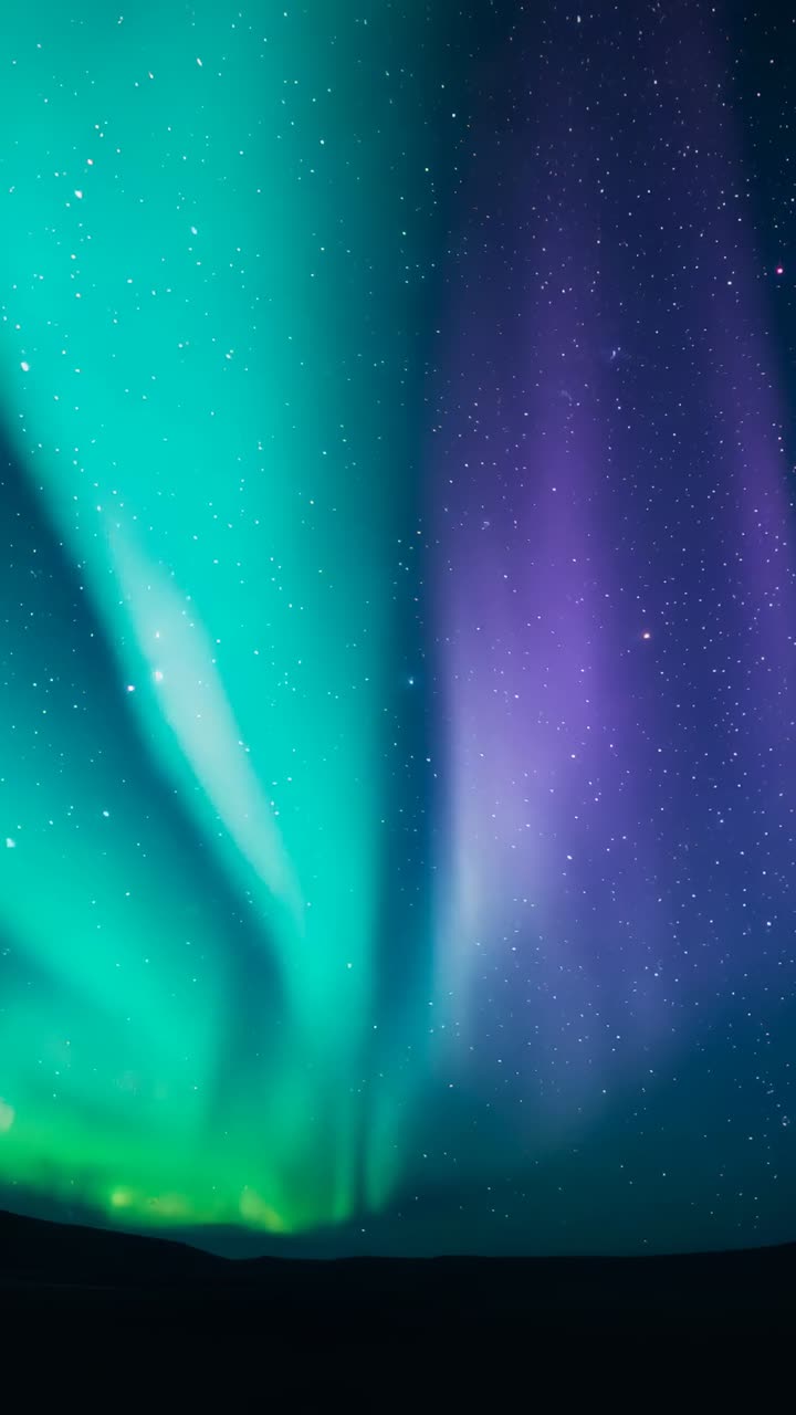 Vertical video: Starting green auroral curtains intertwining with rising purple ribbon above hills