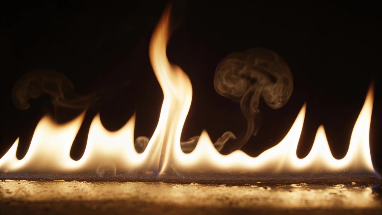Reacting flame line lengthening by air gust in dark studio over fuel bed, forming smoke rings