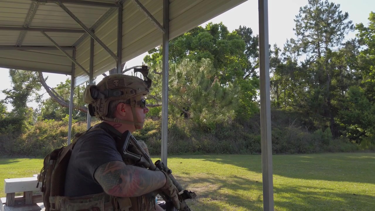 Man in protective gear preparing AR-15 rifle for training.