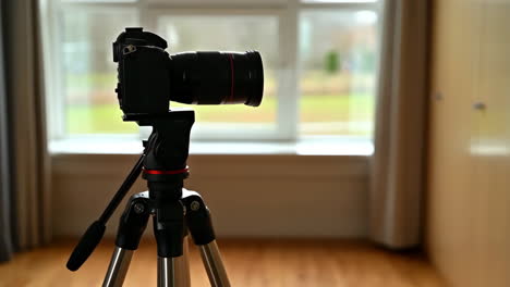 dslr camera on tripod facing a window
