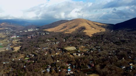 a small town nestled among autumn hills under a cloudy sky, dramatic lighting, aerial view