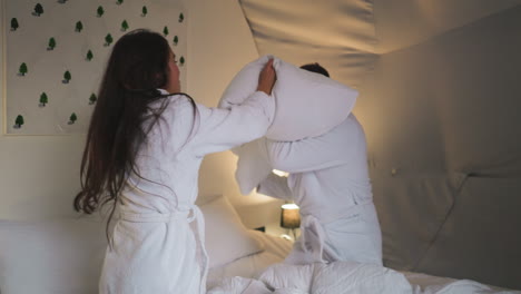 couple having a pillow fight in a cozy bedroom