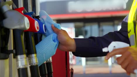 worker cleaning petrol pump at gas station, slow motion close