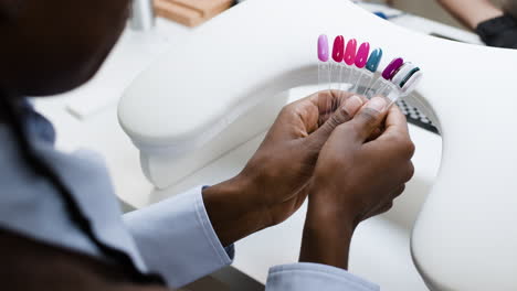 técnico de uñas seleccionando colores de esmalte de uñas