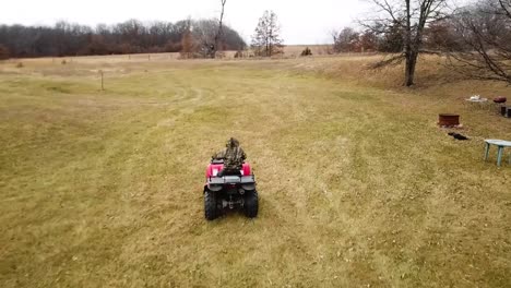 Following-person-driving-four-wheeler-and-flying-up-over-forest-and-lake