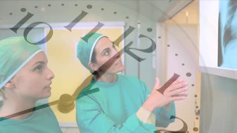 Animation-of-ticking-clock-over-two-diverse-female-surgeons-discussing-over-x-ray-report-at-hospital