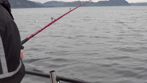 fisherman in a boat spinning reel of a fishing rod in the lake