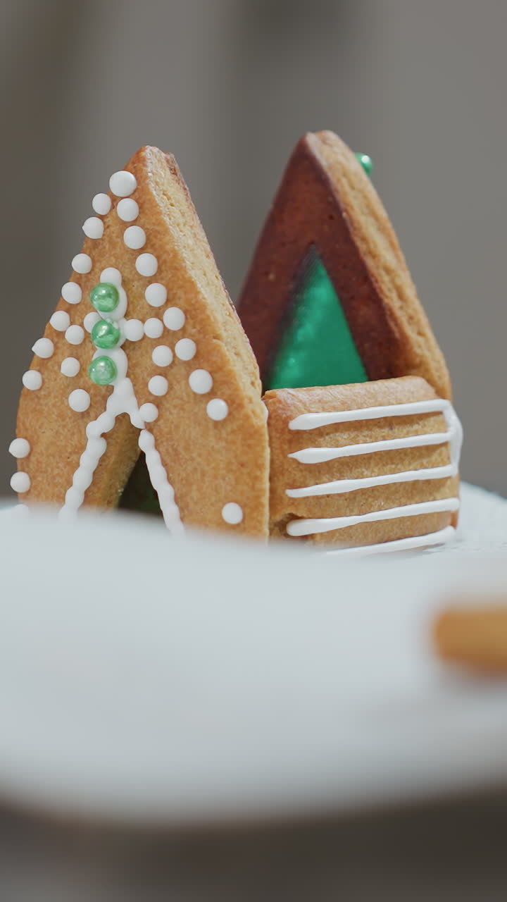 primer plano de una galleta decorada en forma de casa con glaseado verde y blanco de pie con orgullo en papel de pañuelo blanco, rodeada por el efecto bokeh