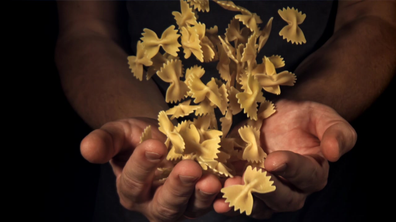 Pasta farfalle al rallentatore che cade in mani a coppa