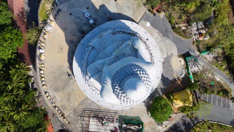 aerial footage showcasing the iconic big buddha statue in phuket, thailand, captured in bright daylight with lush surroundings