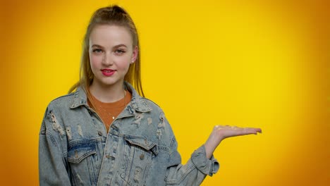 young woman in denim jacket smiling and pointing to the side, with yellow background