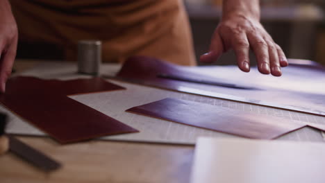 artisan checks up rectangle leather piece at workplace