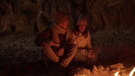 couple enjoying a campfire on the beach at night