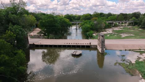 The-Round-Rock-in-Memorial-Park-Chisholm-Trail-in-Texas-aerial-drone-pull-away-over-stream-on-sunny-day-in-4k