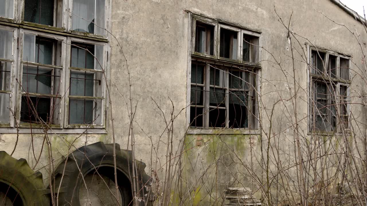 Slow, thrilling arc shot of an abandoned building with cracked windows.