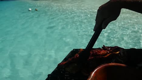 man's hand taking care of a barbecue on his boat. clear water french polynesia