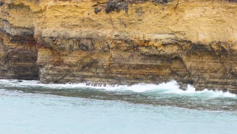 waves rhythmically crash against rugged cliffs under soft daylight, showcasing the natural beauty of great ocean road, australia