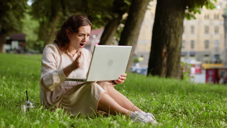 young woman use laptop surprised by bad news, fortune loss, fail, lottery results in urban city park