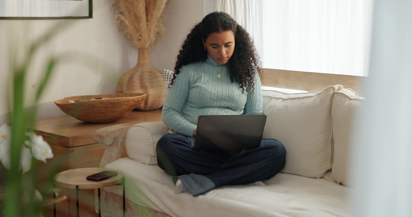 Young Woman Working on Laptop While Sitting on Sofa