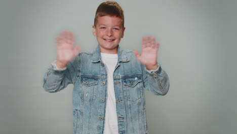 toddler boy smiling friendly at camera and waving hands gesturing hello or goodbye, welcoming