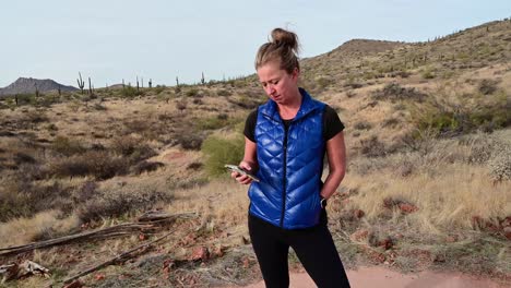 Woman-checking-smart-phone-in-desert-landscape