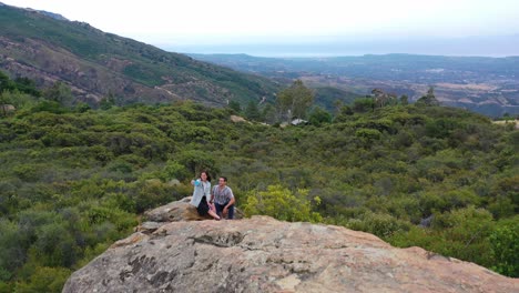 a man and woman climb a rock and take selfie photos overlooking santa barbara california