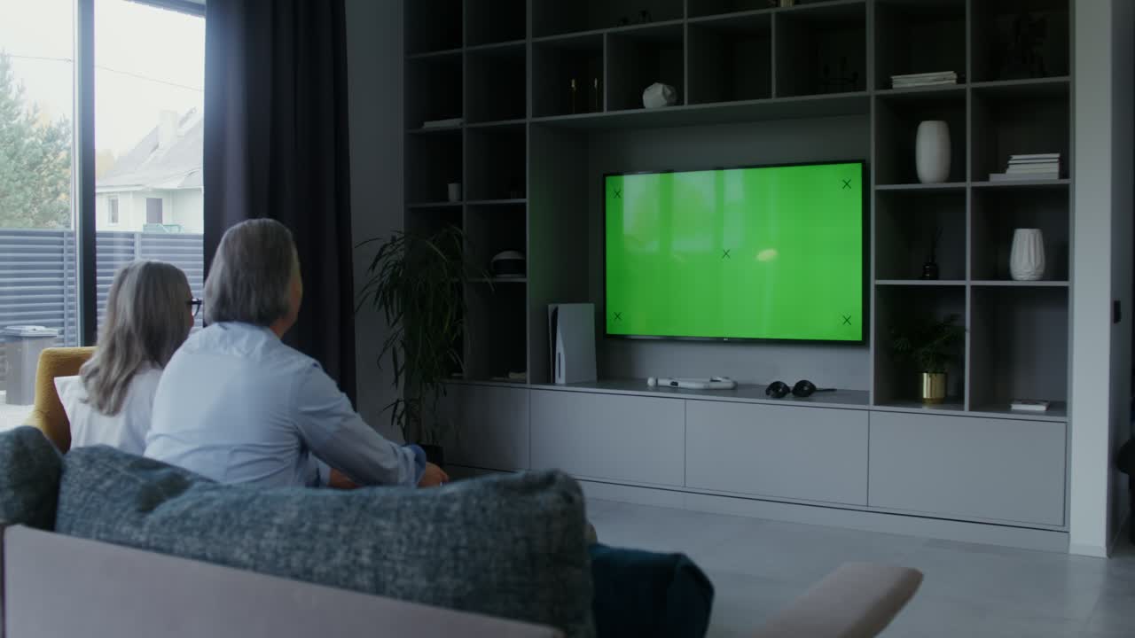 Coppia di anziani guarda la TV con green screen