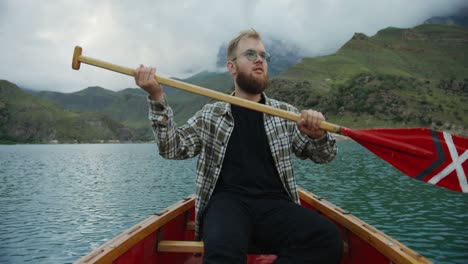 man rowing a boat on a mountain lake