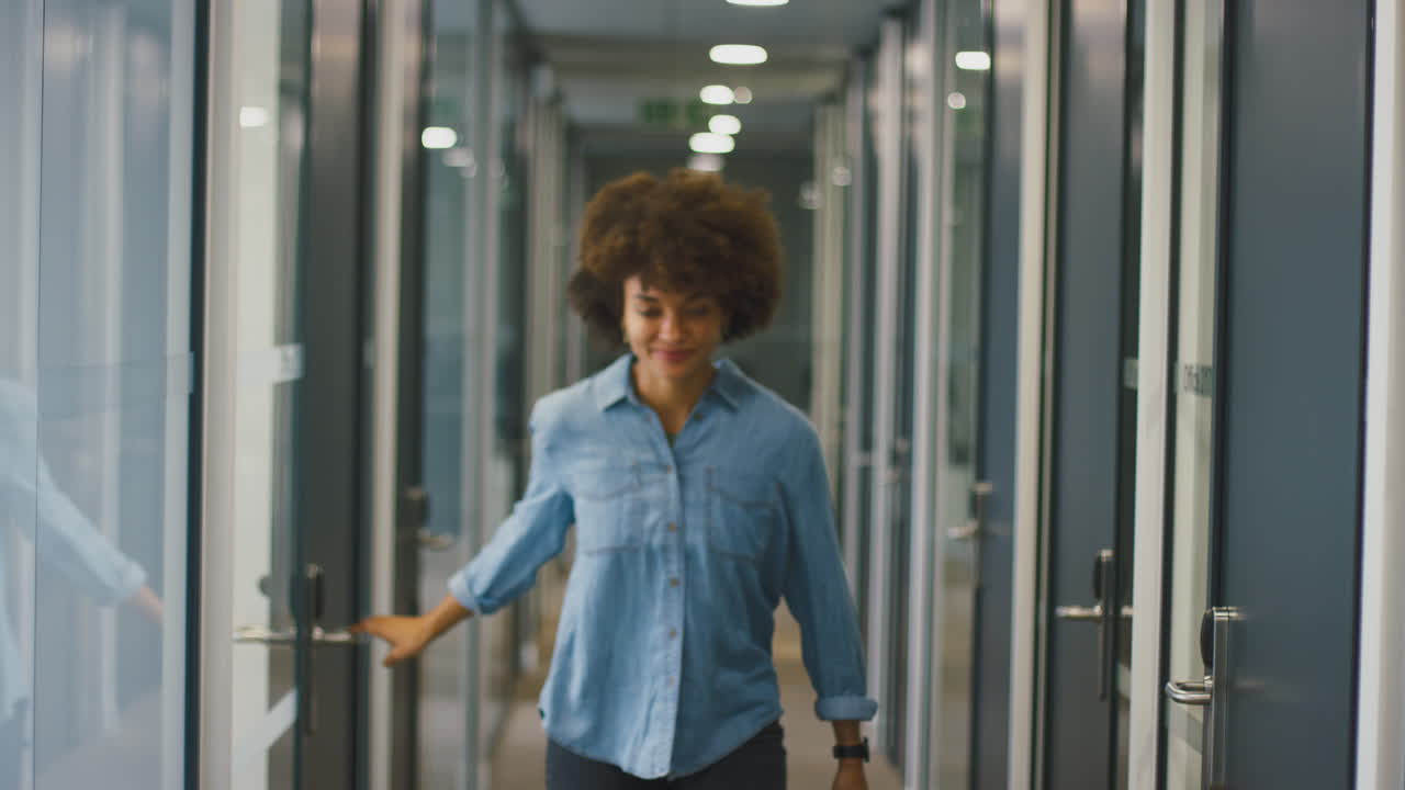 feliz joven mujer de negocios saliendo de la oficina celebrando en el corredor
